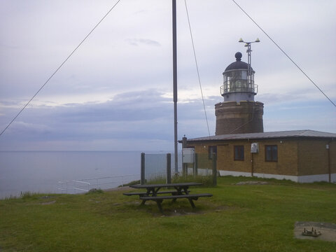 Kullens fyr lighthouse with picnic table on clifftop overlooking the sea, Sk&aring;ne