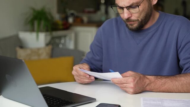 Man entering information from paper documents into laptop