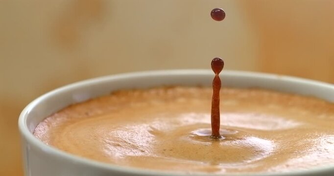 Falling drop into coffee cup super slow motion