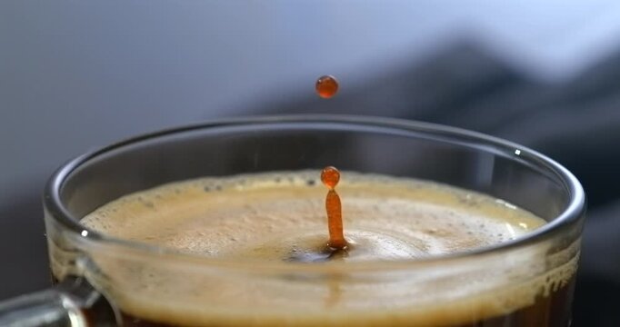 Falling drop into coffee cup super slow motion black background