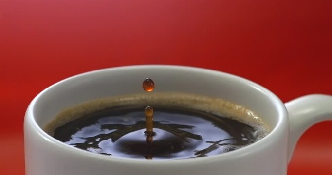 Falling drop into coffee cup super slow motion red background