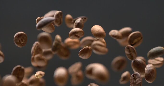 Coffee beans falling through the air in dramatic super slow motion black background