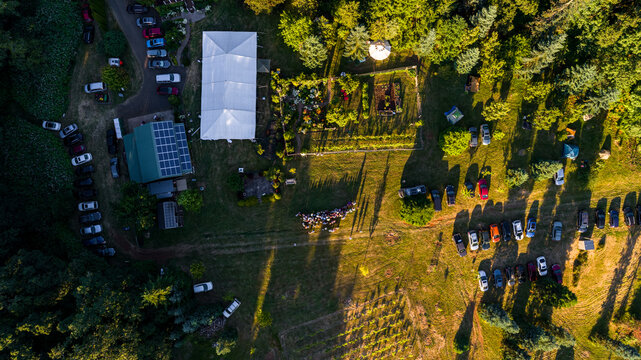 Aerial view of a garden event venue featuring a large white tent, solar panels on a building, and numerous parked cars in a grassy field in Silverton, Oregon, United States.