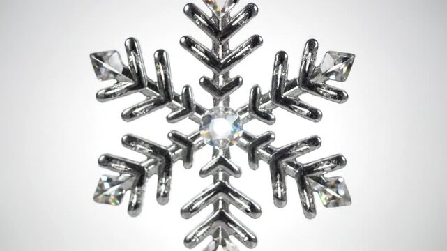 Shining detailed macro shot of a diamond studded silver snowflake showing sparkle and brilliance on a white background