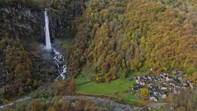 High Altitude Aerial Drone View of Foroglio Waterfall and Alpine Village in Autumn Forest, Switzerland