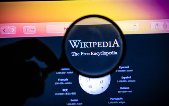 Magnifying glass held over the wikipedia logo on a computer screen