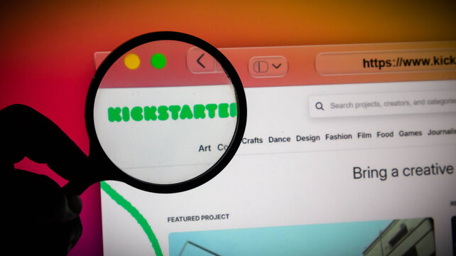 Magnifying glass held over a computer screen showing the kickstarter website