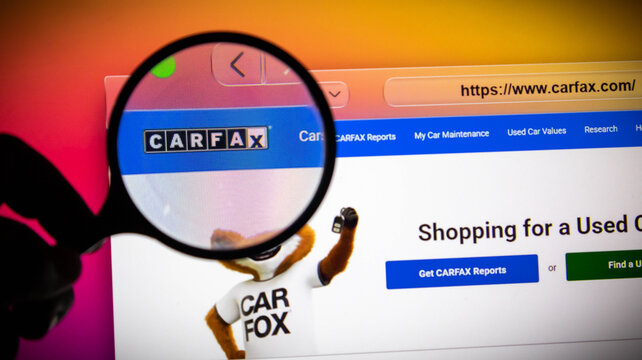 Closeup of a magnifying glass over the carfax website on a computer screen