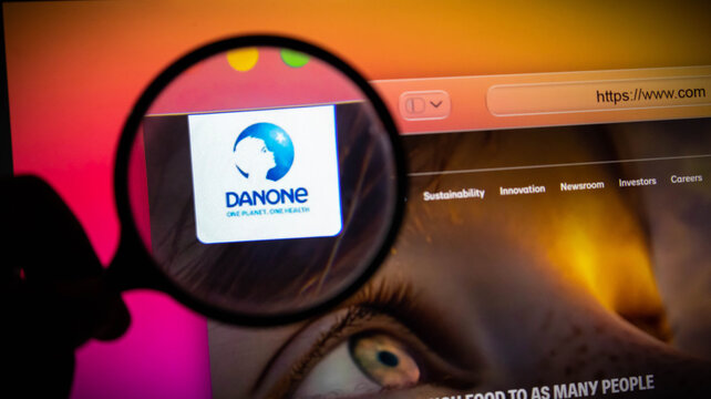 Closeup of a magnifying glass focusing on the danone logo on a computer screen