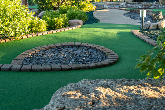 Garden design with green grass and a stone walkway in a mini golf course located in a park, showcasing outdoor landscaping and recreational space horizontal photo