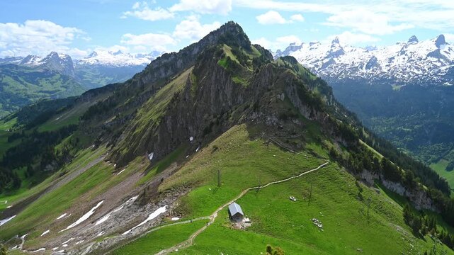Aerial View of Green Alpine Slope with Mountain Hut and Hiking Trail in Swiss Alps, Switzerland