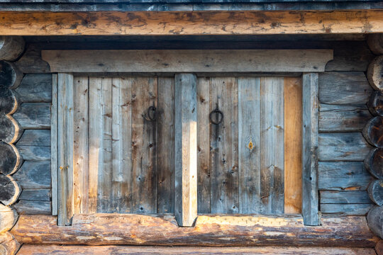 Rustic wooden window shutter on log wall