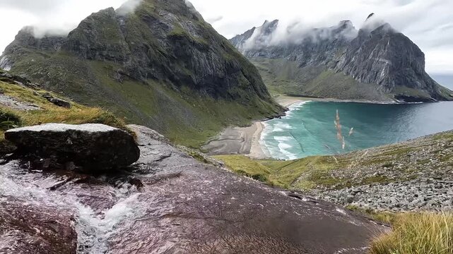 Mountain Stream Flowing Toward Turquoise Kvalvika Beach Below Dramatic Peaks, Lofoten Norway