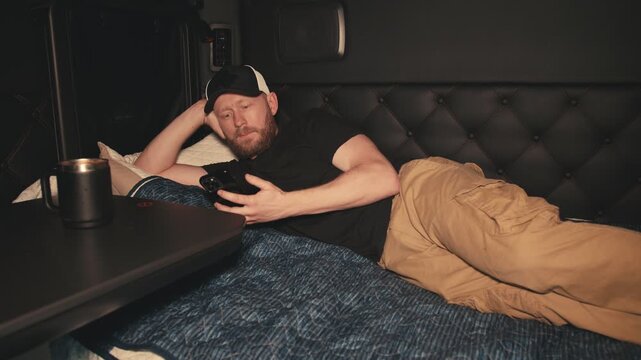 Truck driver resting and using smartphone in sleeper cab