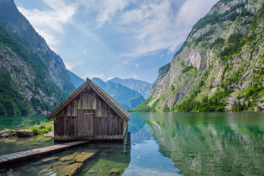 Boat hangar at Obersee mountain lake in Alps Bavaria with broad sky, still water and steep cliffs creating a panoramic Germany alpine landscape.