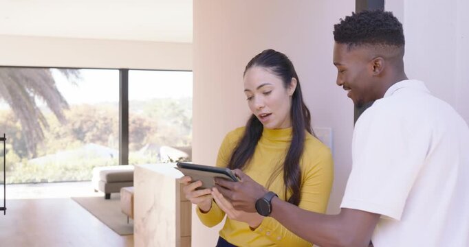 Diverse delivery worker, resident woman yellow top opening door, signing tablet, parcel, copy space