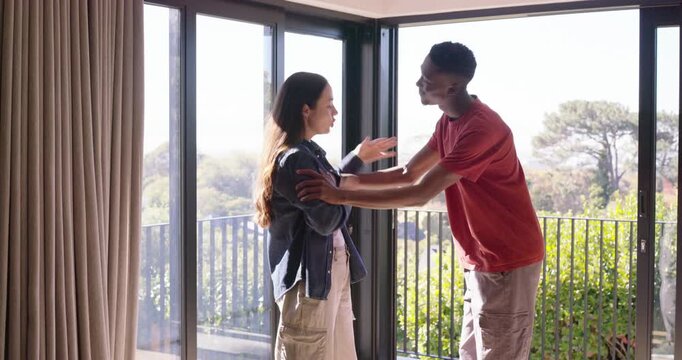 Diverse couple arguing by sliding door he stepping in touching her arms she pushing away wristband