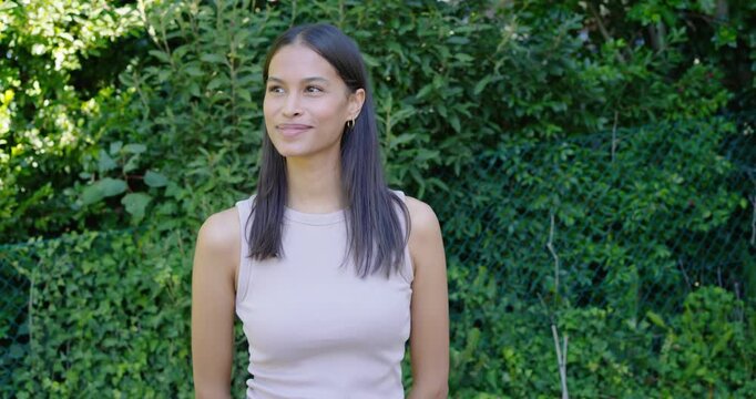 African American woman reacting to offscreen cue shifting gaze, smiling, laughing near hedge