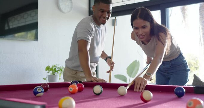 African American couple at magenta pool table practicing, man pointing guiding woman striking balls