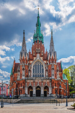 Close view of Saint Joseph Church in Podgorze, Krakow, Poland, showing red brick Gothic architecture, tall steeples, church facade, blue sky, and no people
