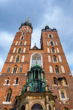 Low angle view of Saint Mary Basilica in Krakow, Poland, with red brick towers, Gothic church facade, blue sky, visible inscription, and no people