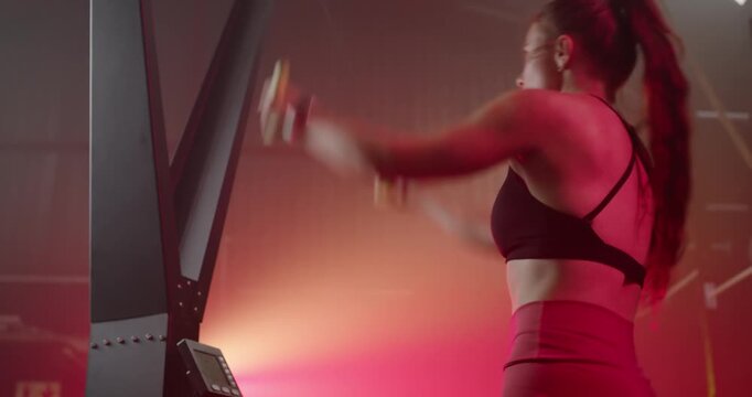 Adult female performing rapid erg pulls after monitor beep, in black bra red leggings