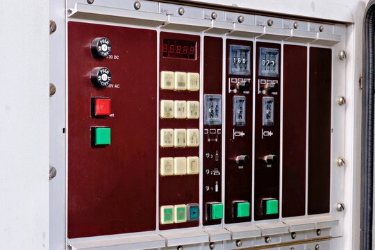 An industrial electronic control module with a red seven-segment digital display, yellow buttons with symbols, counters, and green reset keys.