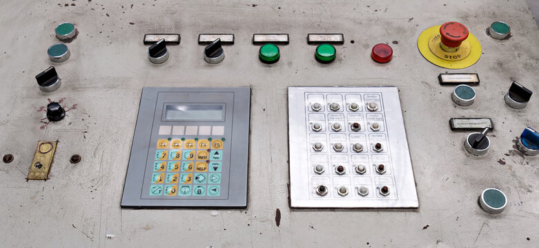 Detailed view of an industrial automated system control board showing a digital display module, custom push-button array, and safety control elements inside a manufacturing plant.