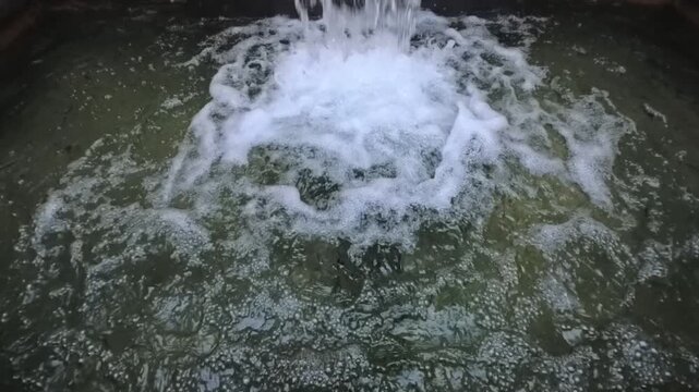 Horizontal 1080p 240fps ultra slow motion video of close up fountain water falling. Narrow abstract shot of bubbling liquid stream splashing with white foam, heavy rushing waves and aqua texture