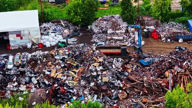 Aerial view of a large scrapyard with piles of metal, vehicles, and machinery outdoors