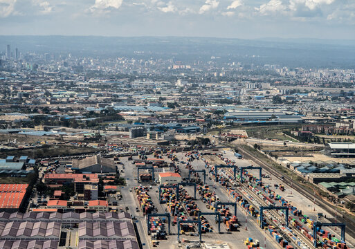 Aerial view of an industrial container terminal with shipping containers, gantry cranes, and railway tracks, set against the urban sprawl of Nairobi, Nairobi County, Kenya.