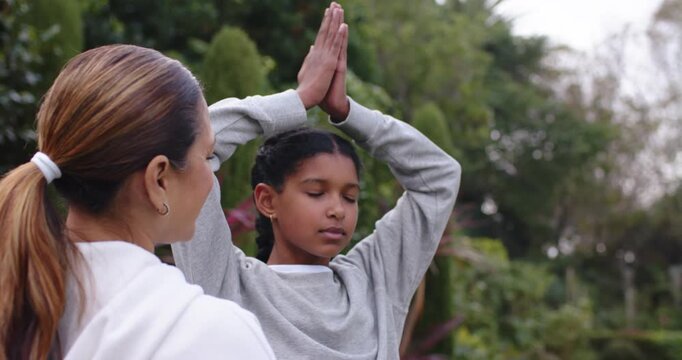 Instructor watching raising arms and guiding youth wrists to align palms in garden grey sweatshirt