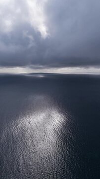 Aerial View Of A Deep Blue Ocean With Shimmering Sunlight Reflecting Off The Water's Surface. - vertical shot