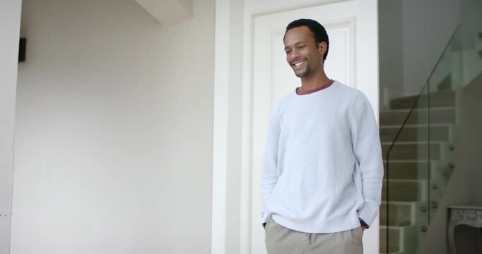 African American man seeing guest at door shifting weight smiling raising hand waving, copy space