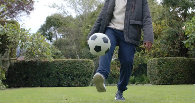 Adult man juggling black-and-white soccer ball, right foot lifting, beginning practice on lawn