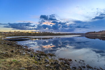 Obraz premium Calm lake at dusk, reflecting blue and orange clouds