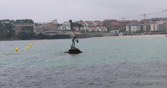 Bronze sculpture of madama de silgar standing on rocks in the water near the beach