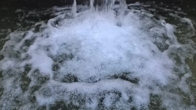 Horizontal 1080p 240fps ultra slow motion video of close up bubbling fountain water splashing into a pool. Abstract cinematic background texture of white foam, liquid streams and rushing aqua waves