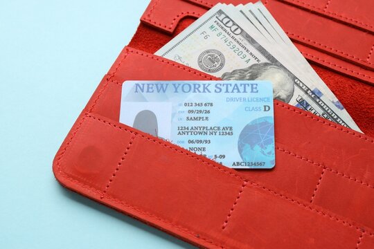 Wallet with driver's licence and money on light blue background, closeup