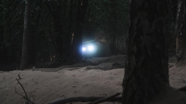 Powerful V8 off-road race car ascending sandy slope in forest at twilight
