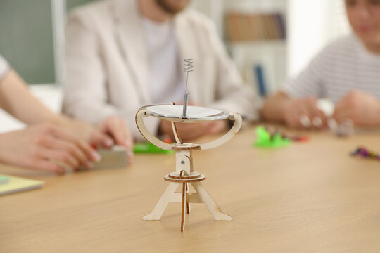 Teacher and students at physics lesson in classroom, focus on solar concentrator model