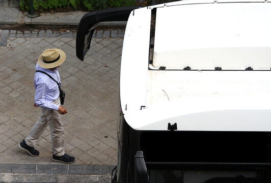 Subir al autob&uacute;s en marquesina bus hombre viajero con sombrero en parada acera 