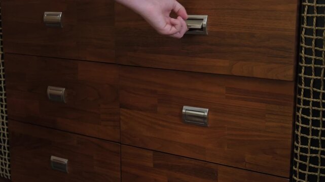 Opening drawers in a wooden cabinet in a room with a patterned wall