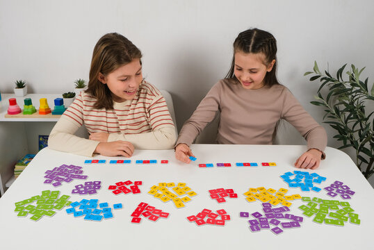 Boy and girl sitting at a table and learning language skills by building words and sentences with colorful letter domino tiles. Educational activity promoting literacy and teamwork.