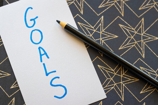Overhead Angle of Goals Text on a Gold Starry Black Background with a Black Pencil 