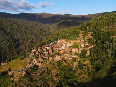 Aerial view of the historic schist village of Talasnal nestled in lush green mountains with traditional stone houses and wind turbines in Lousa, Coimbra, Portugal.
