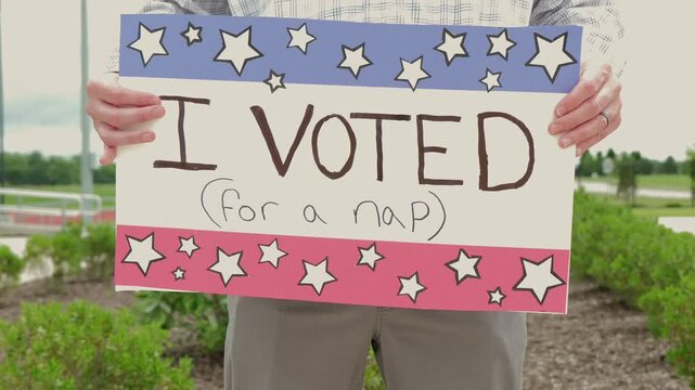 Man holding a humorous, satirical campaign sign reading I Voted for a nap, capturing themes of election fatigue, voting fatigue, and political burnout