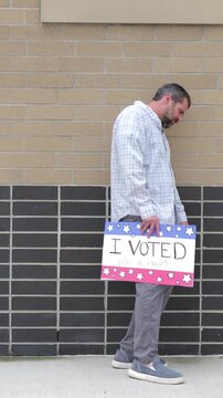 Man holding a humorous, satirical campaign sign reading I Voted for a nap, capturing themes of election fatigue, voting fatigue, and political burnout