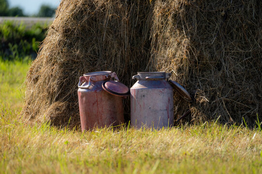 Old Milk Cans Beside Traditional Haystack in Rural Farm Field, Dairy Farming Heritage and Countryside Lifestyle