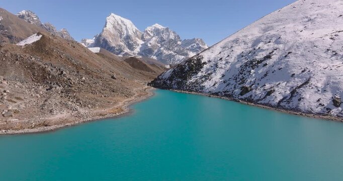 Gokyo Lake, Everest Region, Nepal, drone push-in over the bright turquoise glacial lake toward the snow-covered peak of Cholatse himalayas.